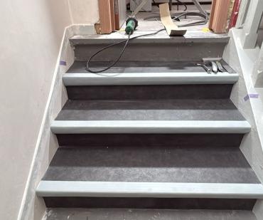 Pose du revêtement PVC gris sur les marches d'un escalier à Jemeppe